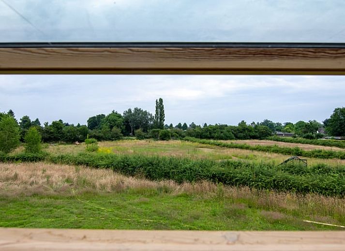 Gezellige binnenruimte van Vakantiehuis in Empe, Gelderse vallei, met open deuren naar terras en uitzicht op de natuur.