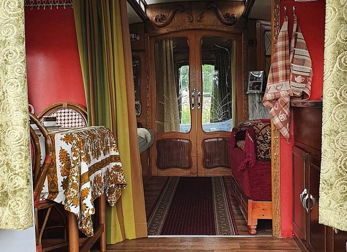 Vakantiehuis in Empe biedt een unieke glamping ervaring met een kleurrijke woonwagen in de Gelderse vallei, omgeven door groen.