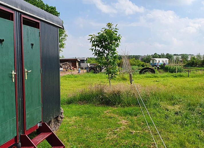 Binnenruimte van Vakantiehuis in Empe toont een gezellige woonwagen met kleurrijke gordijnen en houten details in Gelderland.