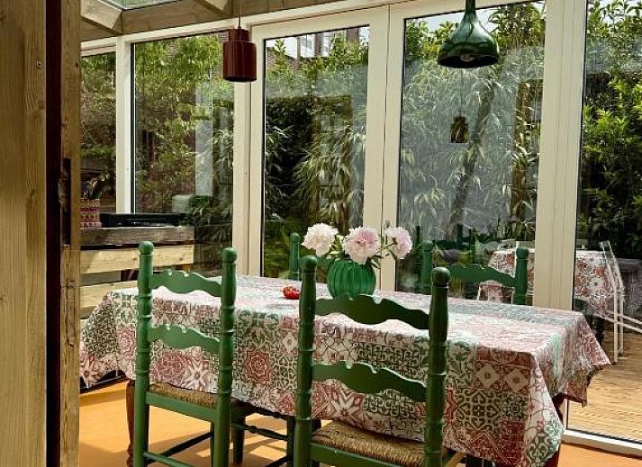 Heller Essbereich im In de Aap - Apartments & Guesthouse, Bergen, Nordholland, mit Glasdach und farbenfrohem Dekor.