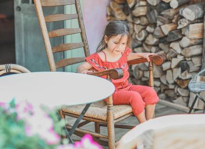 Charmanter Aussenbereich von In de Aap - Apartments & Guesthouse in Bergen, Nordholland, mit bunten Stuehlen und bluehenden Pflanzen.