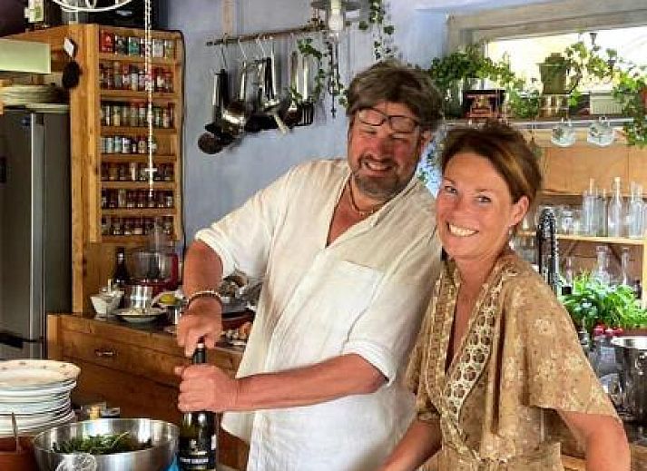 Charmanter Aussenbereich von In de Aap - Apartments & Guesthouse in Bergen, Nordholland, mit bunten Stuehlen und bluehenden Pflanzen.