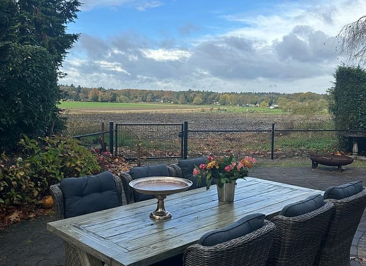 Geniessen Sie den bluehenden Garten im Huisje in Beekbergen, einem Ferienhaus an der Veluwe in Gelderland mit schoener Terrasse und natuerlicher Umgebung.
