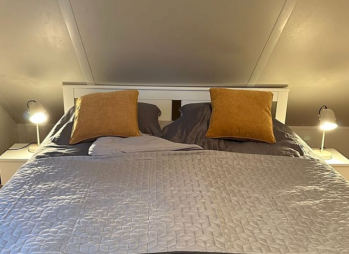 Gemuetliches Schlafzimmer in Cottage in Beekbergen, Ferienhaus in Veluwe, Gelderland, mit bequemem Stuhl und modernem Kleiderschrank.