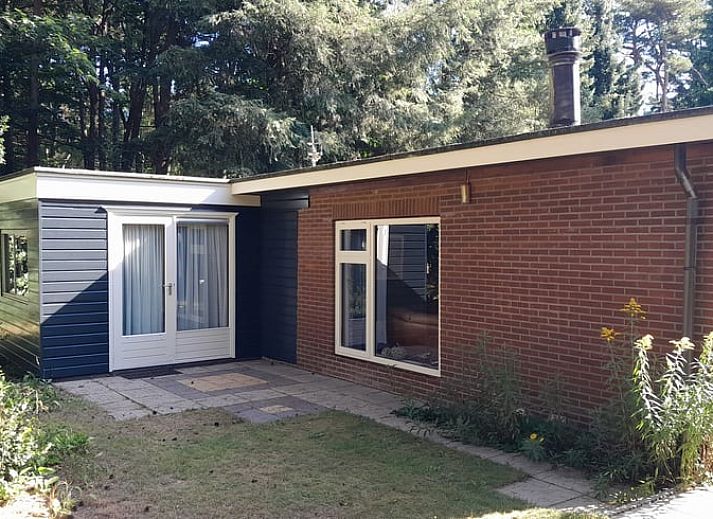 Ferienhaus in Beekbergen, Veluwe, Gelderland, mit einem sonnigen Garten, umgeben von Natur und rustikalen Backsteinmauern.