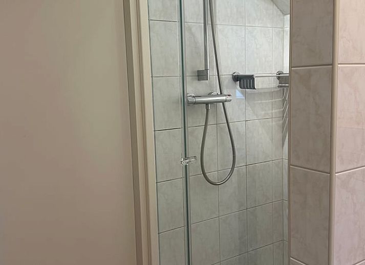 Gemuetliches Wohnzimmer des Ferienhauses in Emst, gelegen in Veluwe, Gelderland, mit bequemen Sitzgelegenheiten und Blick auf die Natur.