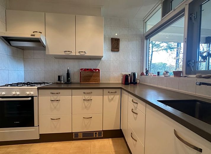 Gemuetliches Wohnzimmer des Ferienhauses in Emst, gelegen in Veluwe, Gelderland, mit bequemen Sitzgelegenheiten und Blick auf die Natur.