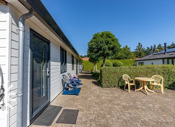 Ingang van vakantiehuis DG1560 in Ermelo, Veluwe, Gelderland, omgeven door groene hagen en schaduwrijke bomen.