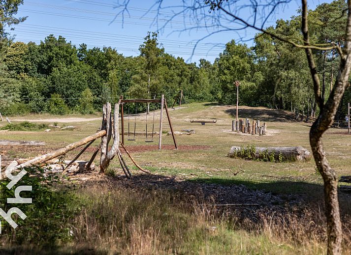 Ingang van vakantiehuis DG1560 in Ermelo, Veluwe, Gelderland, omgeven door groene hagen en schaduwrijke bomen.
