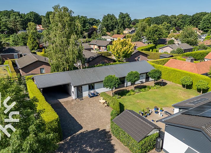 Ingang van vakantiehuis DG1560 in Ermelo, Veluwe, Gelderland, omgeven door groene hagen en schaduwrijke bomen.