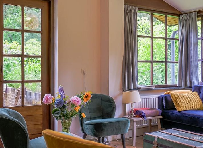 Gezellige woonkamer in Huisje in Ermelo, Veluwe, met kleurrijke stoelen en uitzicht op de natuur in Gelderland.