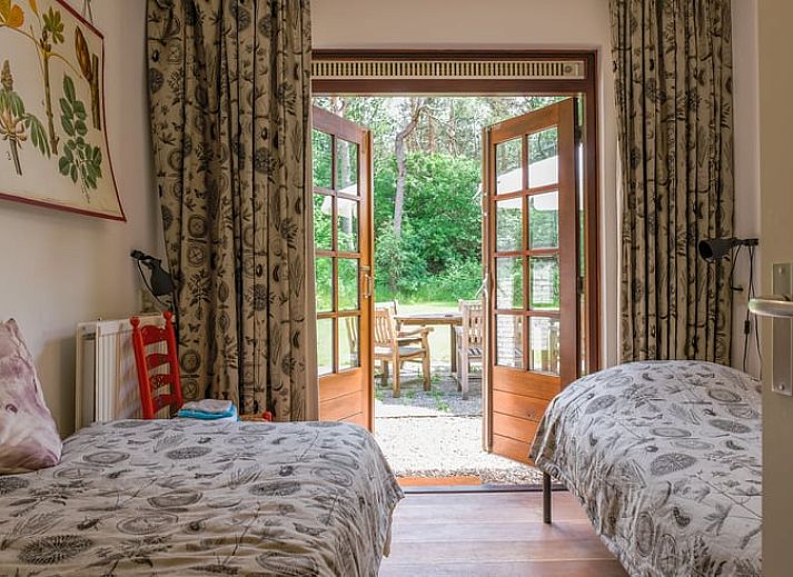 Gezellige woonkamer van Huisje in Ermelo, vakantiehuis op de Veluwe, Gelderland, met uitzicht op de groene natuur door grote ramen.