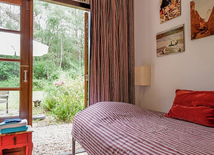 Gezellige woonkamer van Huisje in Ermelo, vakantiehuis op de Veluwe, Gelderland, met uitzicht op de groene natuur door grote ramen.