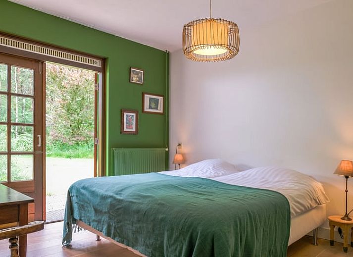 Gezellige woonkamer van Huisje in Ermelo, vakantiehuis op de Veluwe, Gelderland, met uitzicht op de groene natuur door grote ramen.