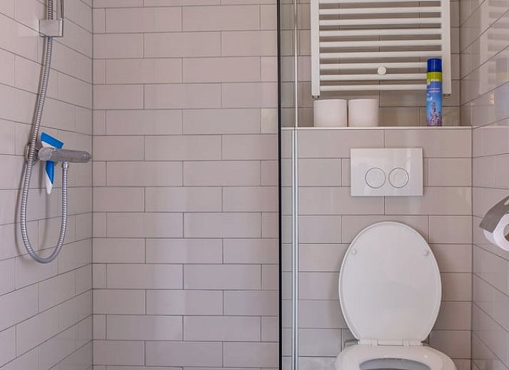 Gezellige binnenruimte van Huisje in Ermelo op de Veluwe, Gelderland, met een sfeervolle open haard en comfortabele stoelen.