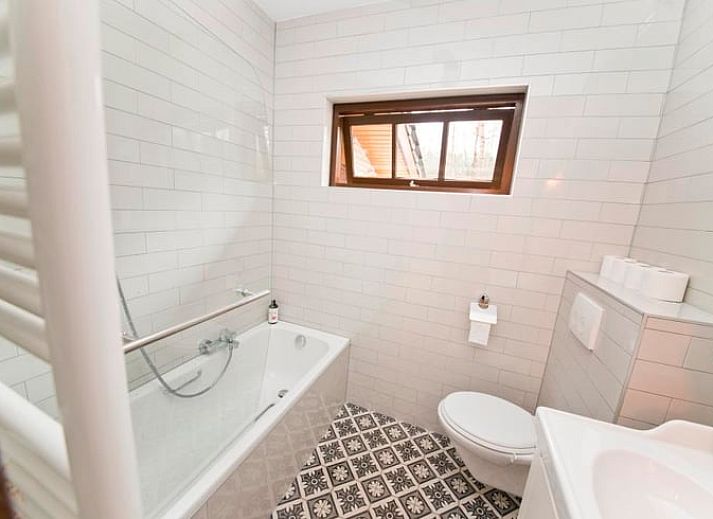 Gezellige binnenruimte van Huisje in Ermelo op de Veluwe, Gelderland, met een sfeervolle open haard en comfortabele stoelen.