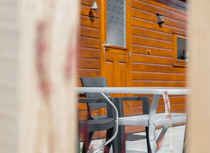 Gemuetliche Terrasse am Ferienhaus Tiny Lodge in Harderwijk, Veluwe, Gelderland mit Liegestuehlen und Esstisch.