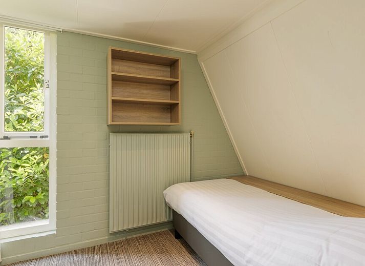 Gemuetliches Wohnzimmer der Veluwe Villa 4B in Hoenderloo mit modernem Kamin und Blick auf die Veluwe Natur.