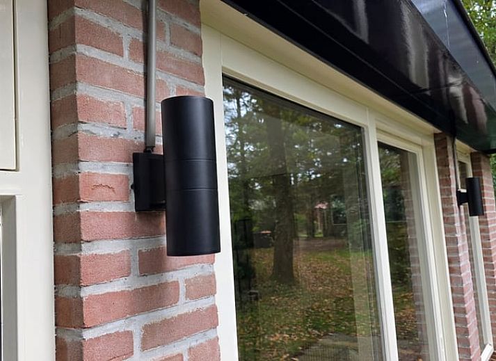 Gezellige binnenruimte van Vakantiehuis in Hoenderloo op de Veluwe, met comfortabele stoel en uitzicht op groene omgeving in Gelderland.