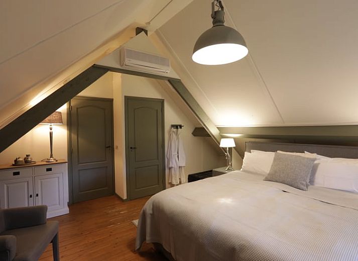 Terrasse des Ferienhauses in Garderen, Ferienunterkunft in der Veluwe, Gelderland, mit Sitzecke und natuerlicher Umgebung.