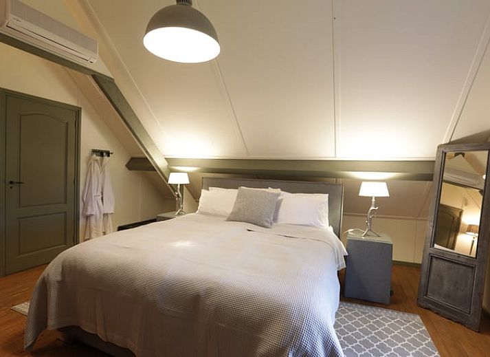 Terrasse des Ferienhauses in Garderen, Ferienunterkunft in der Veluwe, Gelderland, mit Sitzecke und natuerlicher Umgebung.