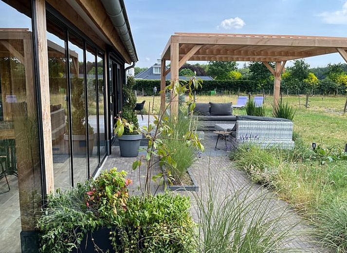 Geniet van de veranda bij Vakantiehuisje in Garderen, Veluwe, met uitzicht op de groene omgeving.