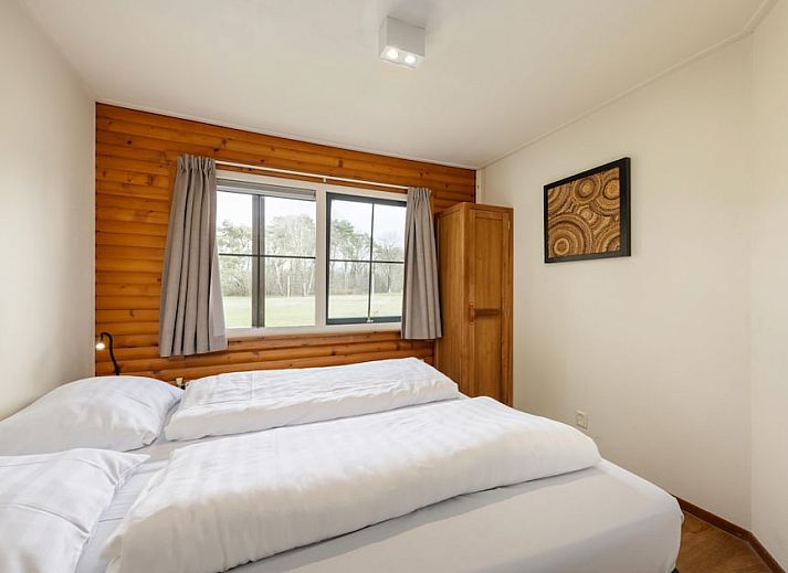 Gemuetliches Wohnzimmer des Bungalows Loghome 6 in Putten, Veluwe, mit Holzinterieur und Blick auf den gruenen Garten.