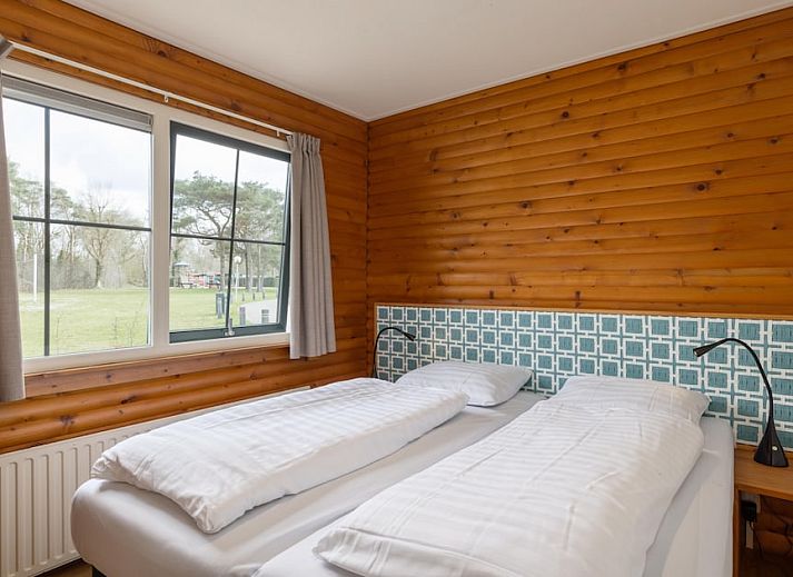 Gemuetliches Wohnzimmer des Bungalows Loghome 6 in Putten, Veluwe, mit Holzinterieur und Blick auf den gruenen Garten.