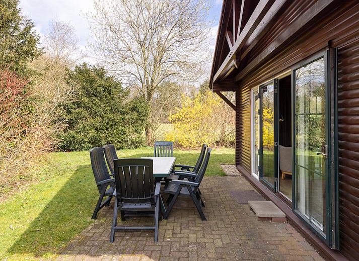 Gemuetliches Wohnzimmer des Bungalows Loghome 6 in Putten, Veluwe, mit Holzinterieur und Blick auf den gruenen Garten.