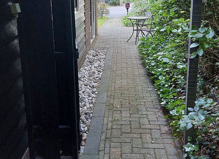 Charmante gevel van Vakantiehuisje in Hulshorst, Veluwe, Gelderland met grasveld en bomen.
