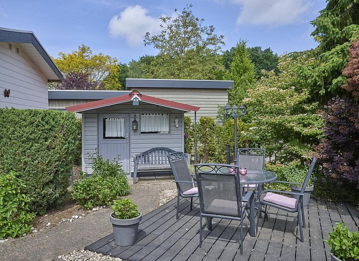 Ontspan op het zonnige terras van vakantiehuis Kerkuil te Hulshorst, Veluwe, omringd door groen.