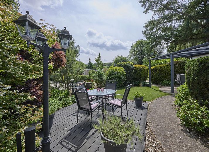 Ontspan op het zonnige terras van vakantiehuis Kerkuil te Hulshorst, Veluwe, omringd door groen.