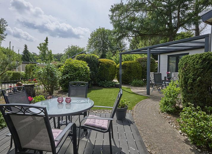 Ontspan op het zonnige terras van vakantiehuis Kerkuil te Hulshorst, Veluwe, omringd door groen.