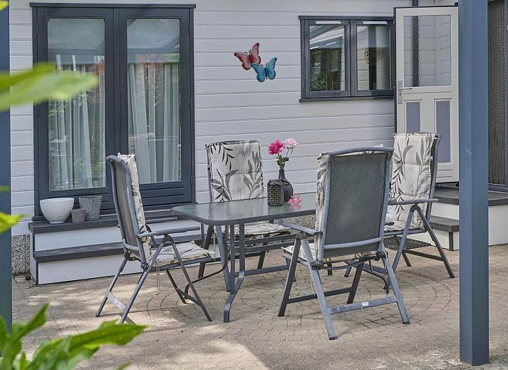 Ontspan op het zonnige terras van vakantiehuis Kerkuil te Hulshorst, Veluwe, omringd door groen.