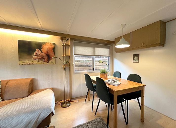 Dining area in chalet Eekhoorn, Hulshorst, Veluwe with wooden table and green chairs.