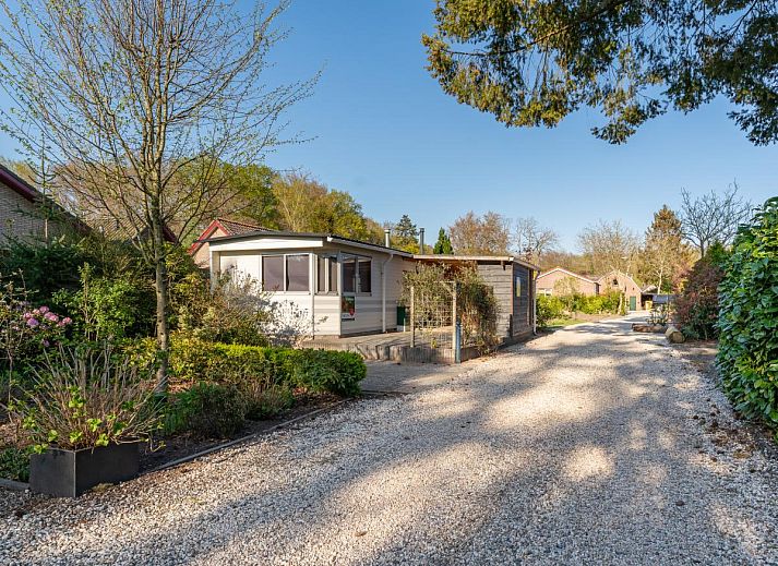 Dining area in chalet Eekhoorn, Hulshorst, Veluwe with wooden table and green chairs.