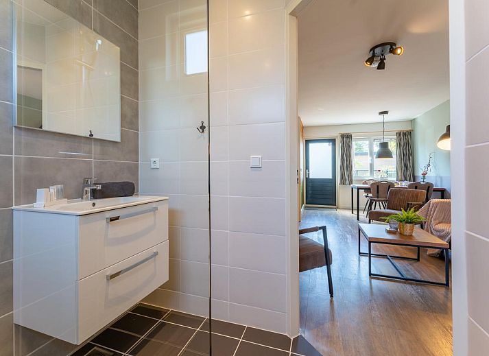 Geraeumige Terrasse des Ferienhauses Pimpelmees in Hulshorst, Veluwe mit Sitzgelegenheit und Sonnenschirm.