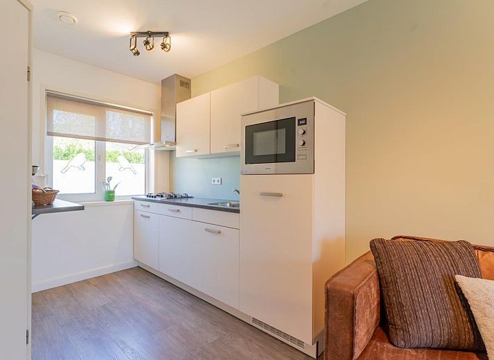 Terrace of vacation home Koolmees in Hulshorst, Veluwe with tables and umbrellas for relaxing outdoor seating.