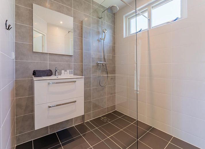 Terrace of vacation home Koolmees in Hulshorst, Veluwe with tables and umbrellas for relaxing outdoor seating.