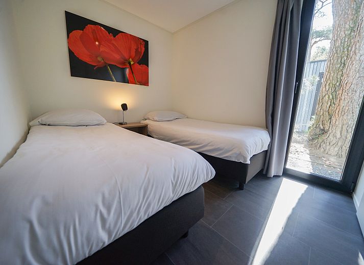 Gezellige woonkamer in Chalet in Otterlo, Veluwe met veel lichtinval en comfortabele zitplaatsen.