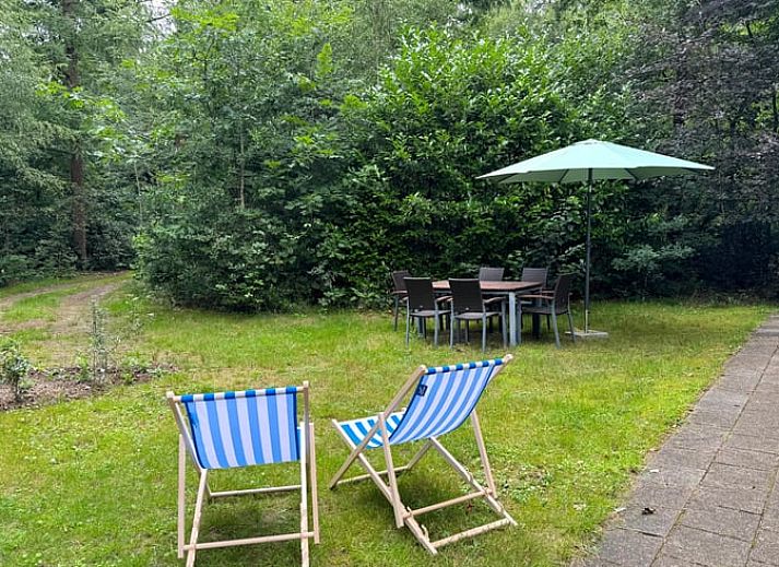 Vakantiehuis in Otterlo op de Veluwe, Gelderland, omgeven door natuur met een uitnodigend terras en comfortabele ligstoelen.