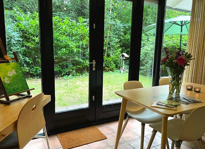 Ontspan in de groene tuin van Vakantiehuis in Otterlo, Veluwe, Gelderland, met comfortabele zitruimte en parasol voor een rustgevende ervaring.