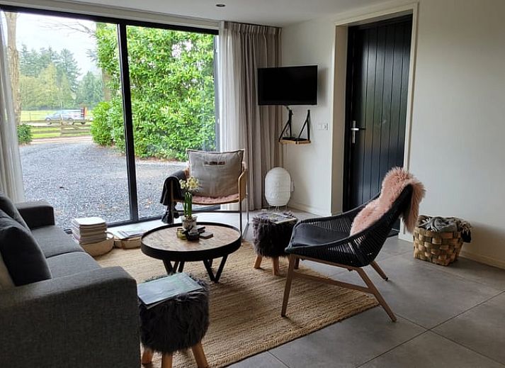 Cozy porch of Holiday Home in Epe in the Veluwe, Gelderland, with fireplace and views of the wooded landscape.