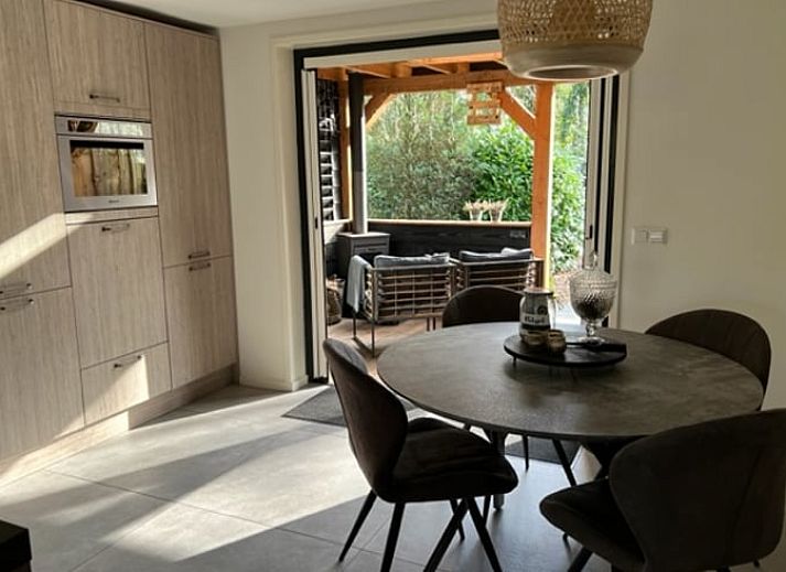 Cozy porch of Holiday Home in Epe in the Veluwe, Gelderland, with fireplace and views of the wooded landscape.