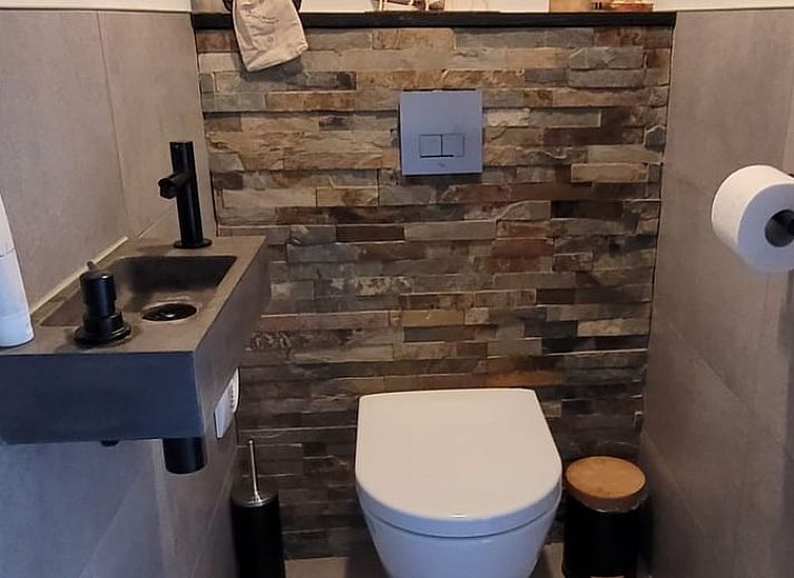 Cozy interior of Cottage in Epe, Veluwe with warm wood stove and drinks board, perfect for relaxation in Gelderland.