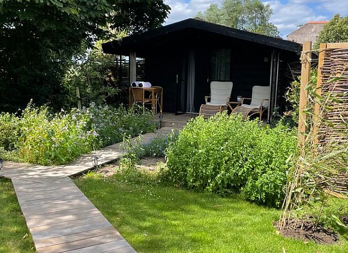 Entspannen Sie sich im Garten des Ferienhauses in Scherpenzeel, Gelderland mit Sauna und Whirlpool, das in der gruenen Veluwe-Region liegt.