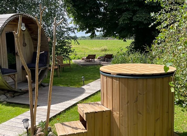 Entspannen Sie sich im Garten des Ferienhauses in Scherpenzeel, Gelderland mit Sauna und Whirlpool, das in der gruenen Veluwe-Region liegt.