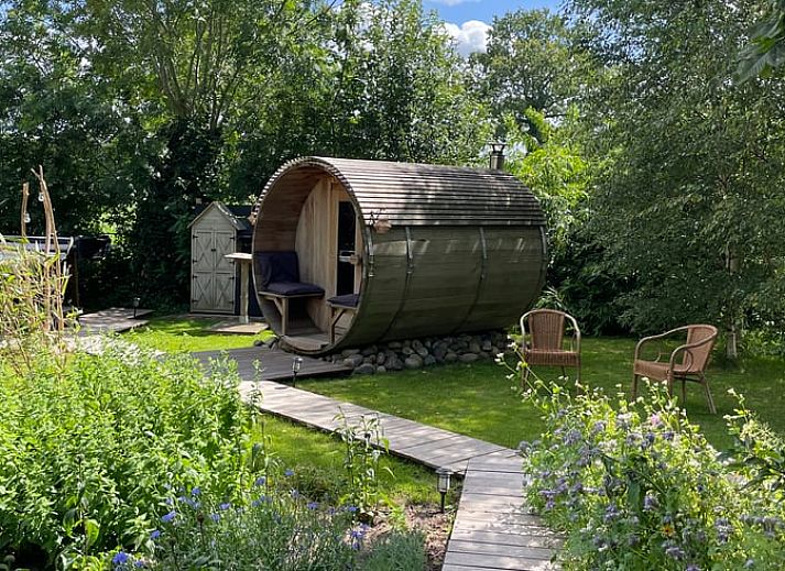 Entspannen Sie sich im Garten des Ferienhauses in Scherpenzeel, Gelderland mit Sauna und Whirlpool, das in der gruenen Veluwe-Region liegt.