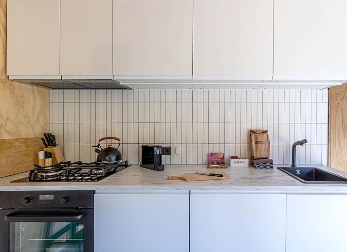 Moderne keuken in vakantiehuis Mos, Nunspeet, Veluwe met strakke witte kasten en houten accenten voor een gezellige sfeer.