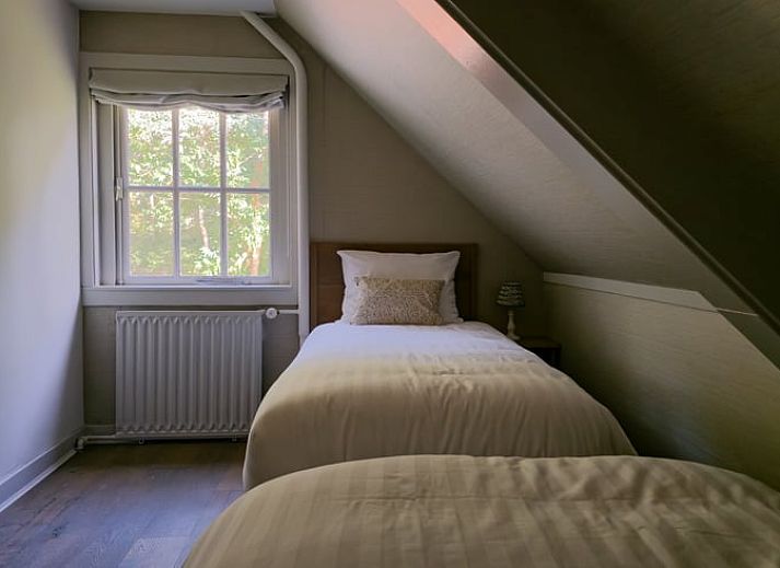 Stijlvolle woonkamer in Huisje in Lunteren, Veluwe, met comfortabele leren bank en uitzicht op de tuin.